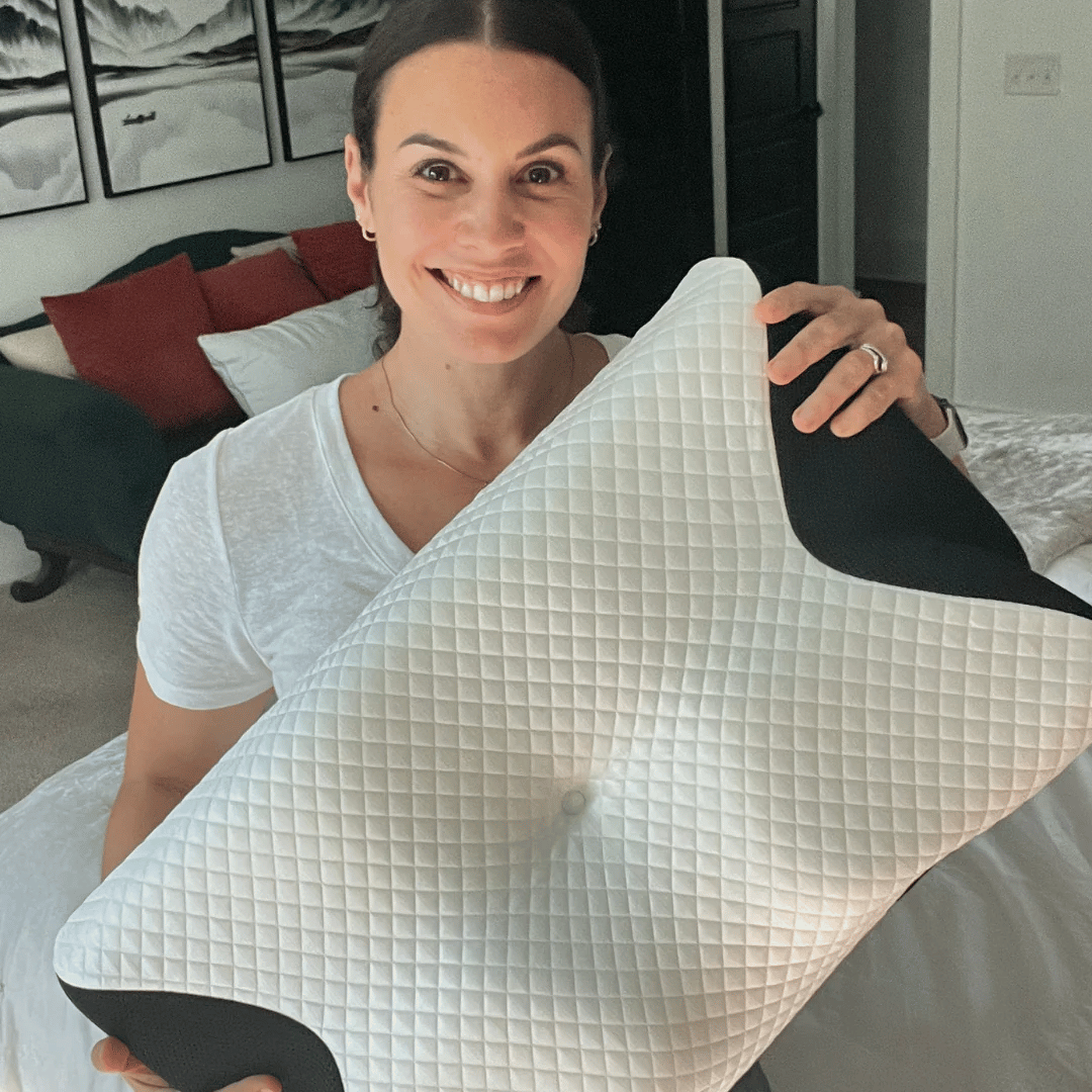Woman holding The Neck Therapy Pillow showing ergonomic butterfly shape